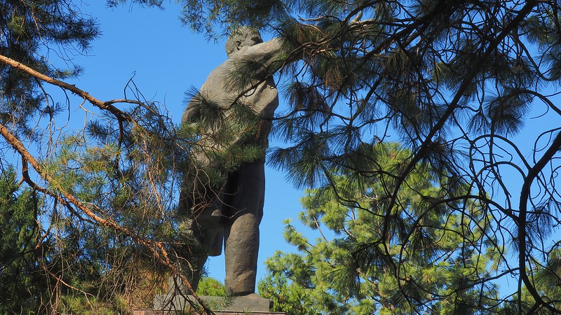 Lenin statue monument as viewed through tree branches in Bishkek, Kyrgyzstan